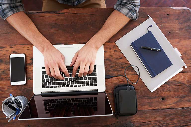 Employee sitting at a desk typing on a laptop.